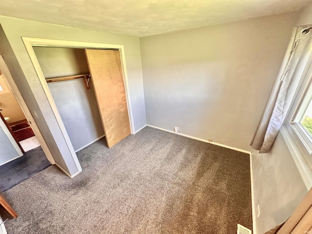unfurnished bedroom featuring baseboards, carpet, a closet, and visible vents
