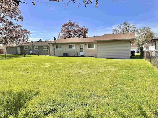 rear view of house with a lawn, fence, and central air condition unit