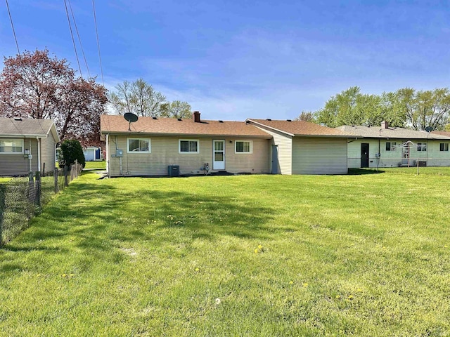 rear view of house featuring a yard, fence, and central AC unit