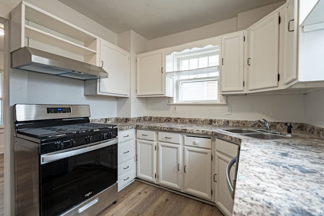 kitchen featuring wall chimney range hood, dark wood-style flooring, stainless steel gas range oven, a sink, and white cabinetry