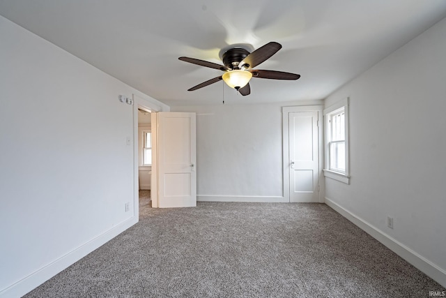 unfurnished bedroom with carpet flooring, baseboards, and multiple windows
