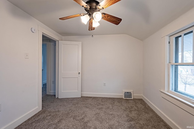 interior space with ceiling fan, visible vents, baseboards, lofted ceiling, and carpet