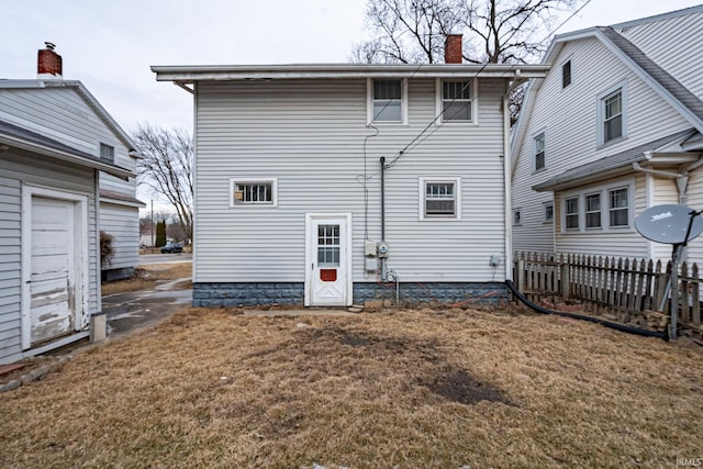 rear view of property with fence, a chimney, and a yard
