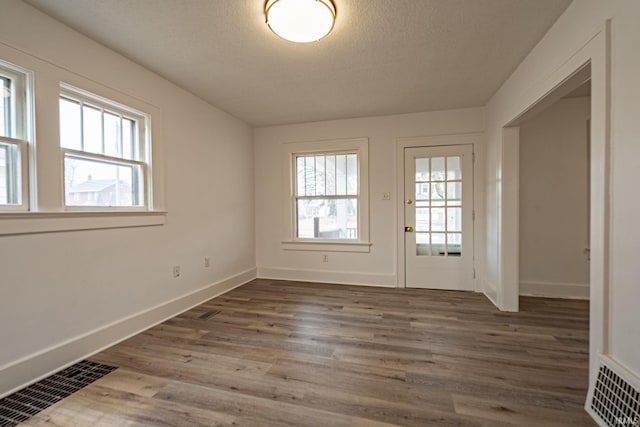 entryway featuring a textured ceiling, baseboards, wood finished floors, and visible vents