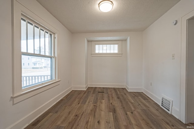 spare room with baseboards, a textured ceiling, visible vents, and wood finished floors
