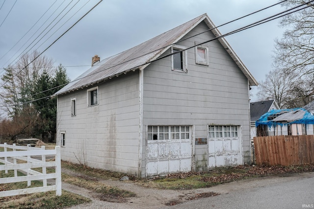 view of side of home with fence, a chimney, and an attached garage