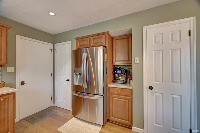 kitchen with light countertops, stainless steel refrigerator with ice dispenser, recessed lighting, and light wood-type flooring