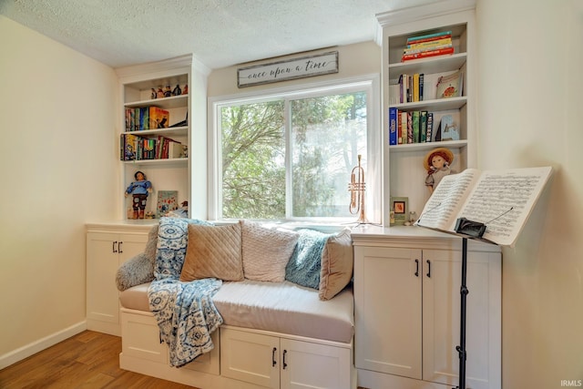sitting room with a textured ceiling, baseboards, and wood finished floors