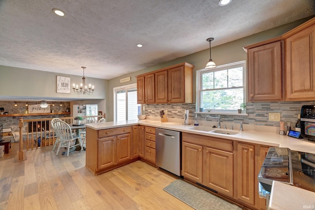 kitchen featuring appliances with stainless steel finishes, a sink, a textured ceiling, a peninsula, and backsplash