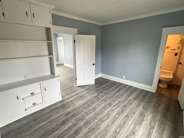 unfurnished bedroom with crown molding, dark wood-style flooring, baseboards, and ensuite bathroom