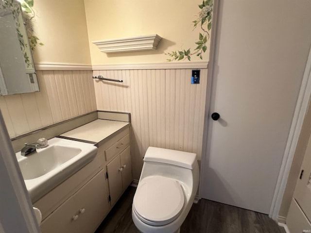 bathroom featuring a wainscoted wall, vanity, toilet, and wood finished floors