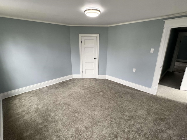 empty room featuring baseboards, ornamental molding, and dark colored carpet