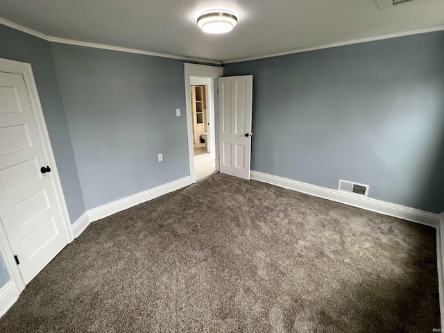 empty room featuring baseboards, ornamental molding, dark colored carpet, and visible vents