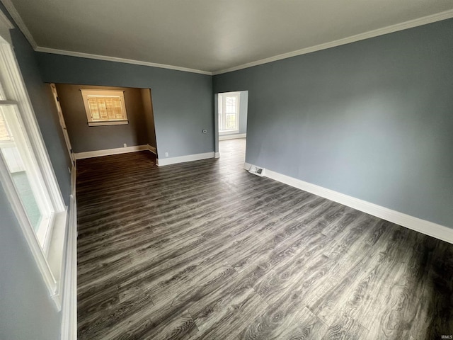 empty room with baseboards, dark wood finished floors, and crown molding