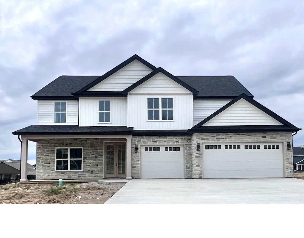 craftsman inspired home with driveway, french doors, and stone siding