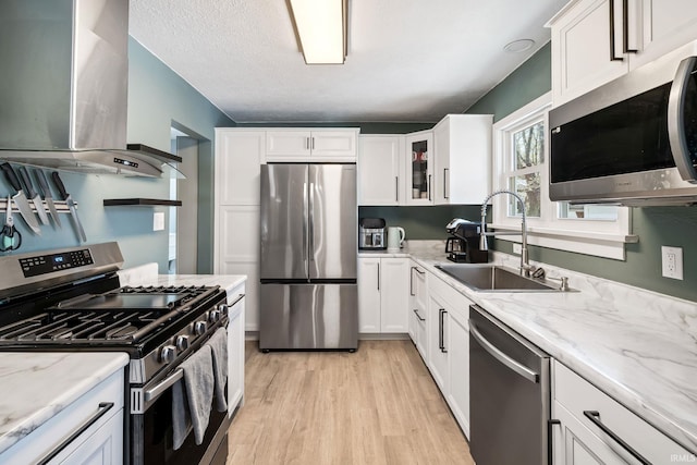 706 Ruse St, North Manchester, IN 46962 - kitchen featuring wall chimney range hood, white cabinets, a sink, light wood-style flooring, and appliances with stainless steel finishes