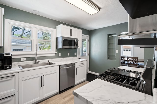 706 Ruse St, North Manchester, IN 46962 - kitchen featuring white cabinets, light stone countertops, appliances with stainless steel finishes, a sink, and light wood finished floors