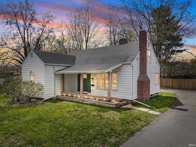 706 Ruse St, North Manchester, IN 46962 - ranch-style house featuring covered porch, a chimney, a front yard, fence, and a shingled roof