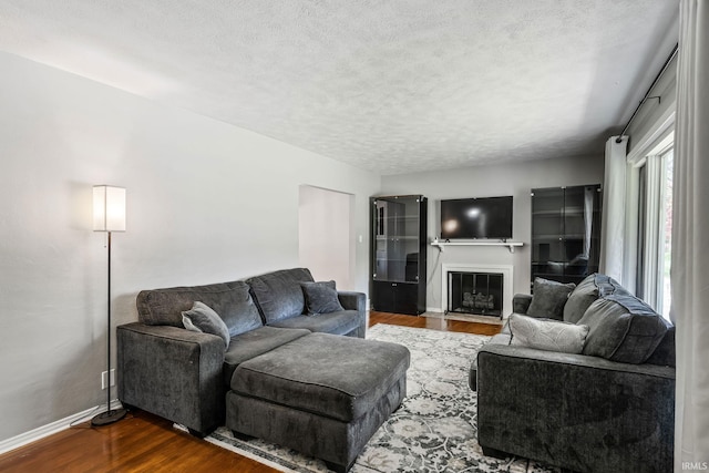 706 Ruse St, North Manchester, IN 46962 - living room featuring baseboards, a textured ceiling, dark wood finished floors, and a fireplace with flush hearth