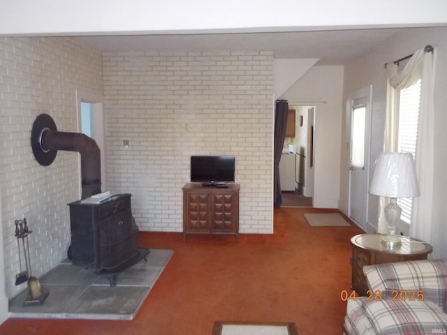 living area featuring carpet flooring, brick wall, and a wood stove
