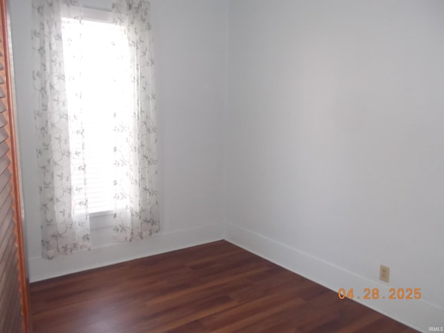spare room with baseboards and dark wood-style floors
