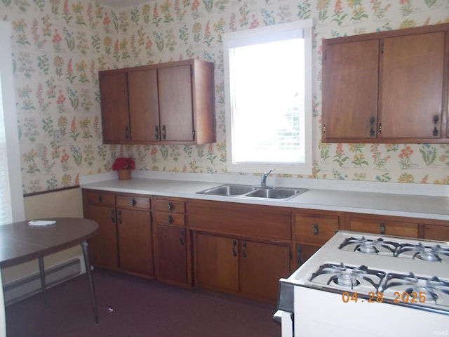 kitchen featuring wallpapered walls, white gas stove, and a sink