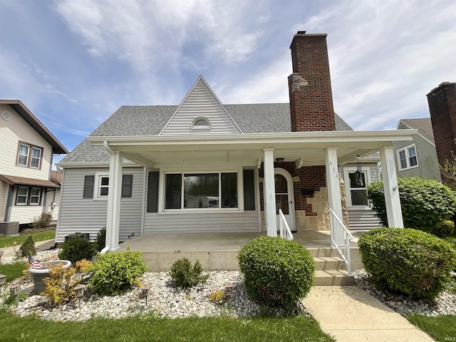 view of front of property with a porch, a chimney, and roof with shingles