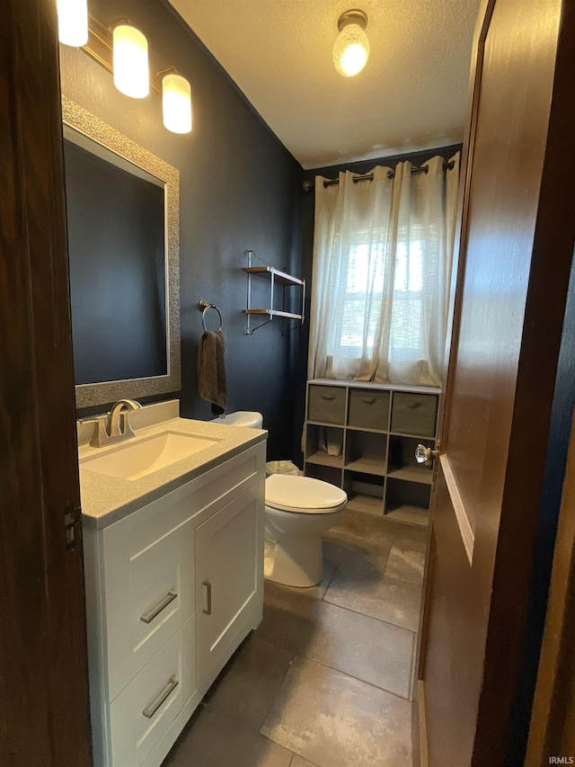 half bath with vanity, toilet, tile patterned floors, and a textured ceiling