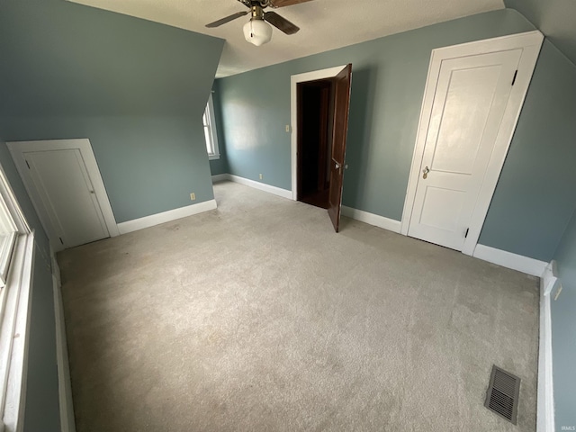 additional living space with visible vents, a ceiling fan, baseboards, and light colored carpet