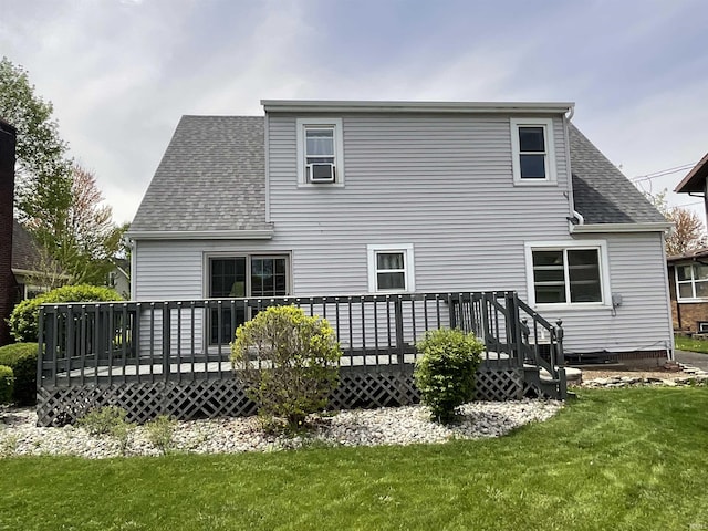 rear view of house featuring roof with shingles, a lawn, and a deck