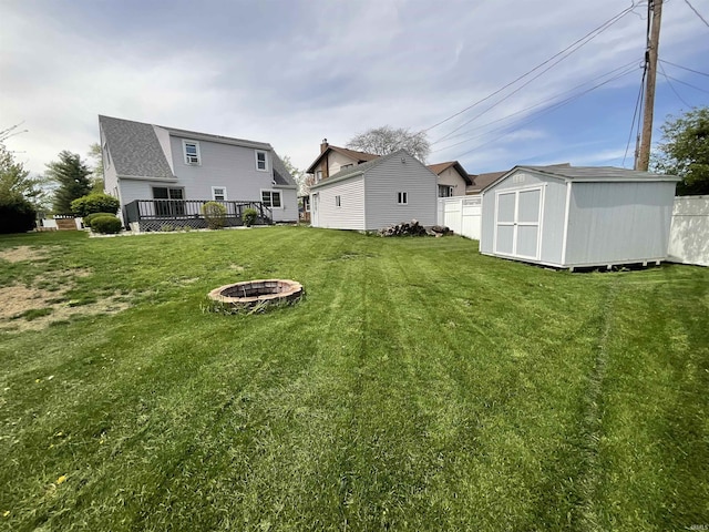 view of yard featuring an outbuilding, a fire pit, fence, and a storage shed