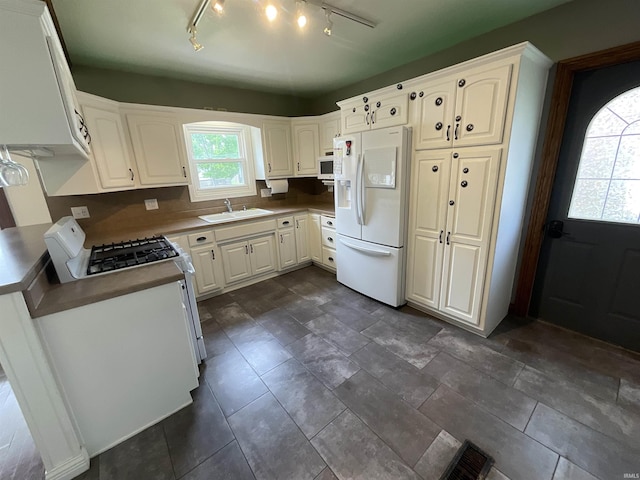 kitchen with white appliances, white cabinetry, visible vents, and a sink