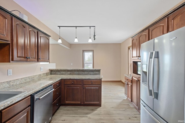 kitchen with hanging light fixtures, light wood-type flooring, rail lighting, light stone counters, and stainless steel appliances