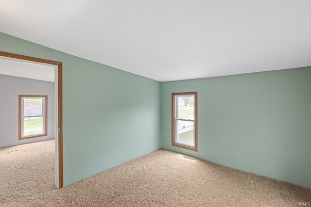 spare room featuring a healthy amount of sunlight, carpet, and visible vents