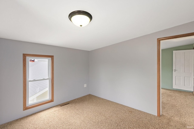 spare room featuring visible vents and light carpet