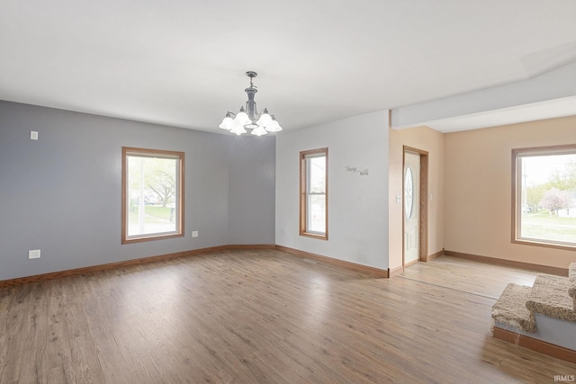 spare room with light wood-style floors, baseboards, and a notable chandelier