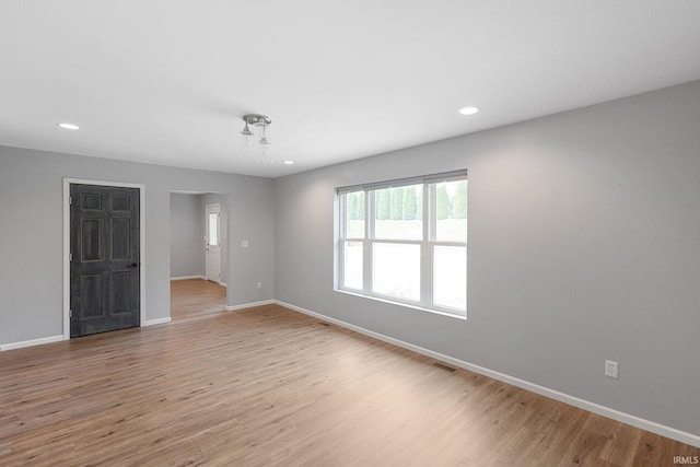 empty room with baseboards, light wood-type flooring, recessed lighting, and visible vents