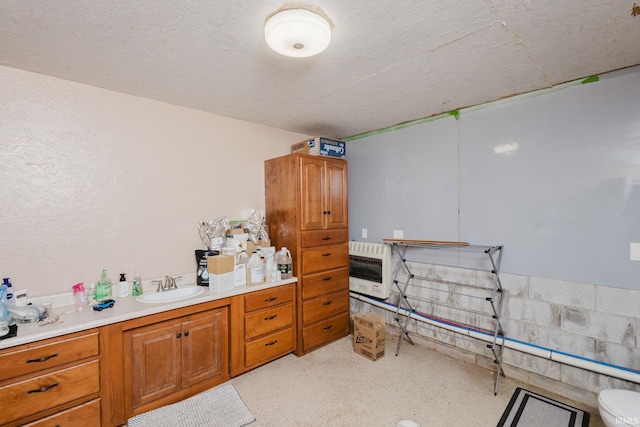interior space featuring heating unit, vanity, and toilet