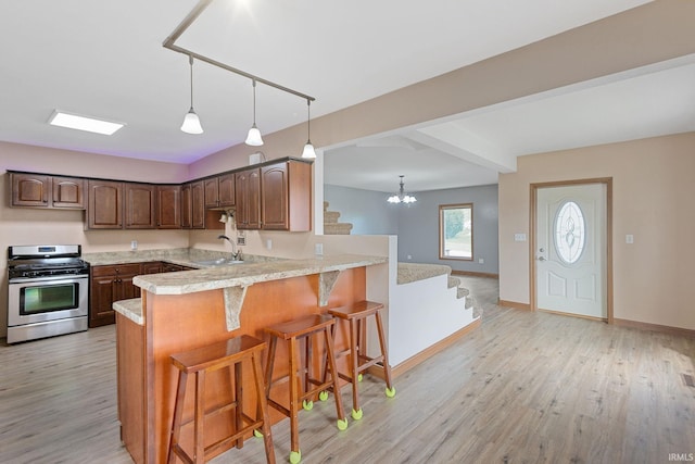 kitchen with light countertops, a kitchen breakfast bar, light wood-style flooring, and stainless steel gas stove
