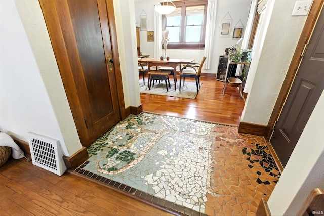 corridor with baseboards, visible vents, and hardwood / wood-style floors
