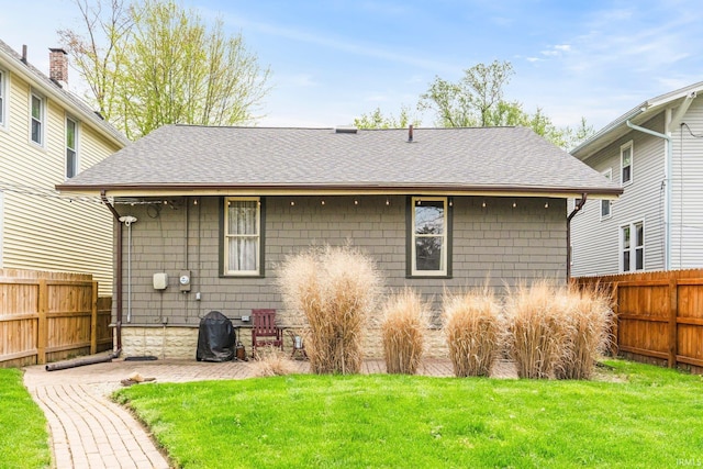 back of property with fence private yard, roof with shingles, and a lawn