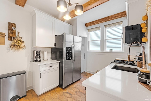 kitchen with stainless steel appliances, beamed ceiling, white cabinetry, and tasteful backsplash