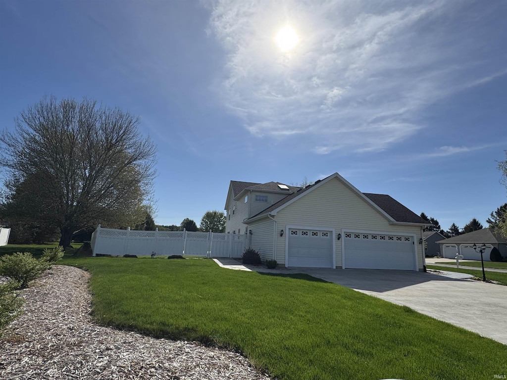 view of side of home featuring a garage, fence, a lawn, and driveway