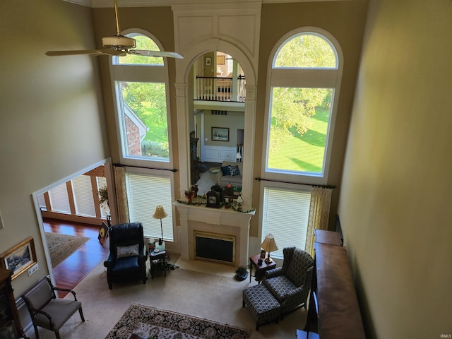 living area featuring a fireplace with flush hearth, a high ceiling, and a ceiling fan