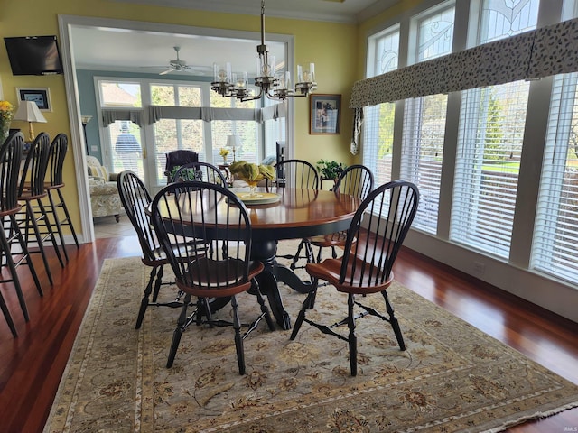 dining room with baseboards, ornamental molding, ceiling fan with notable chandelier, and wood finished floors