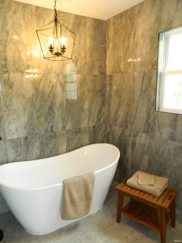 full bathroom featuring tile walls, a chandelier, and a freestanding bath