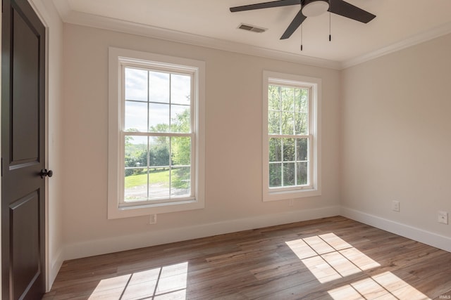 unfurnished room with crown molding, a ceiling fan, baseboards, wood finished floors, and visible vents