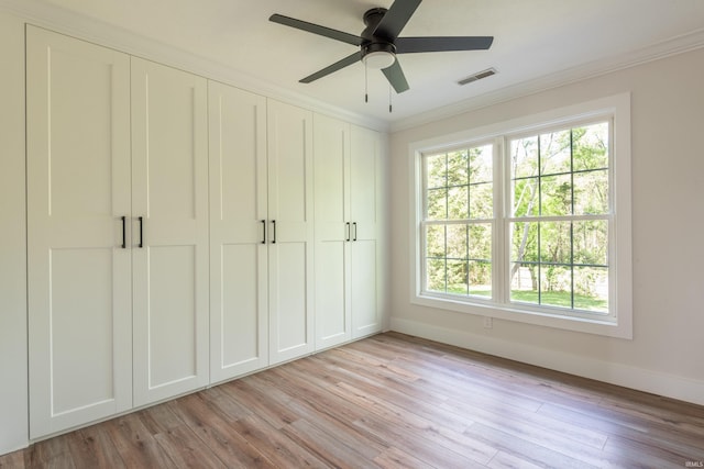 unfurnished bedroom with baseboards, visible vents, ornamental molding, and multiple windows