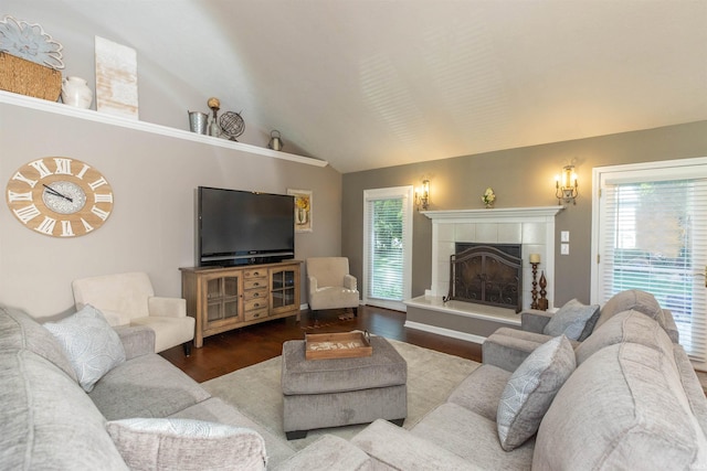 living area featuring a tiled fireplace, wood finished floors, and lofted ceiling