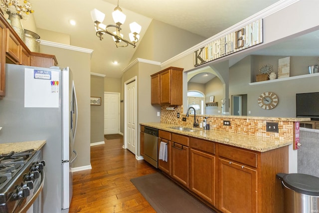 kitchen with light stone counters, a sink, stainless steel appliances, a peninsula, and decorative backsplash